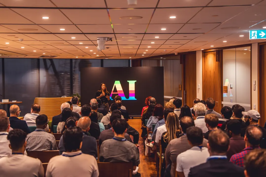 Audience watching a talk in front of the AI on Apple logo